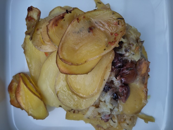 KI generiert: Gebackene Kartoffelscheiben mit Gemüse und Käse auf einem weißen Teller.