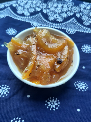 KI generiert: Eine kleine weiße Schale mit einer gelben, marmeladenartigen Substanz auf einem blauen, gemusterten Tuch.